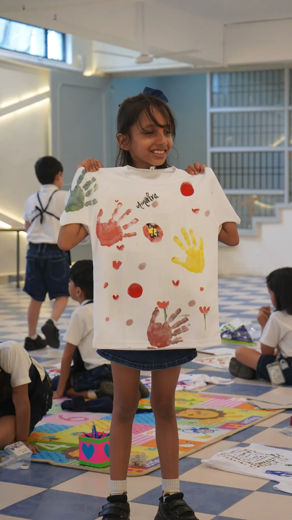 A smiling student holding up her hand-printed T-shirt