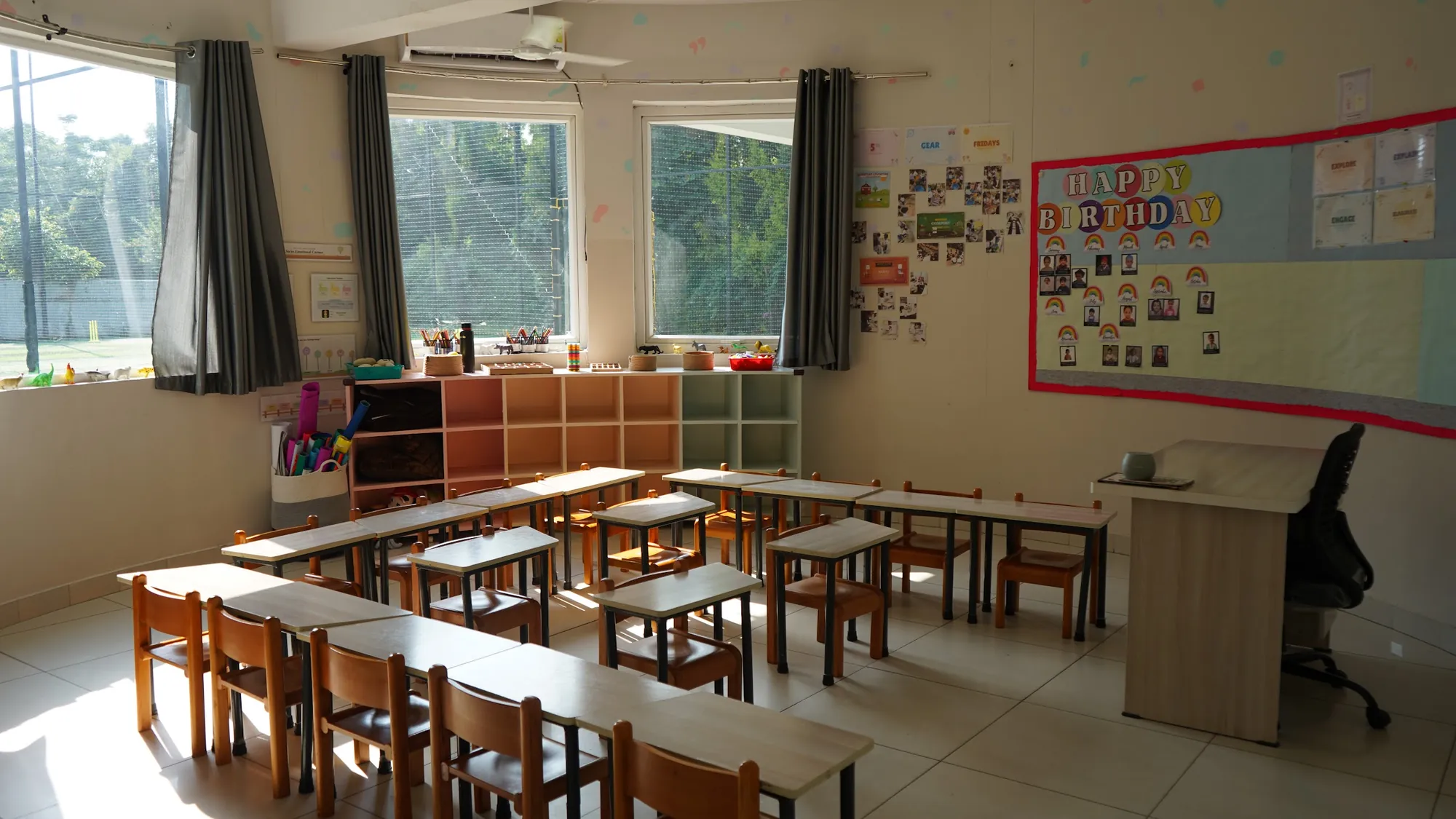 A bright primary classroom with low desks and a birthday board