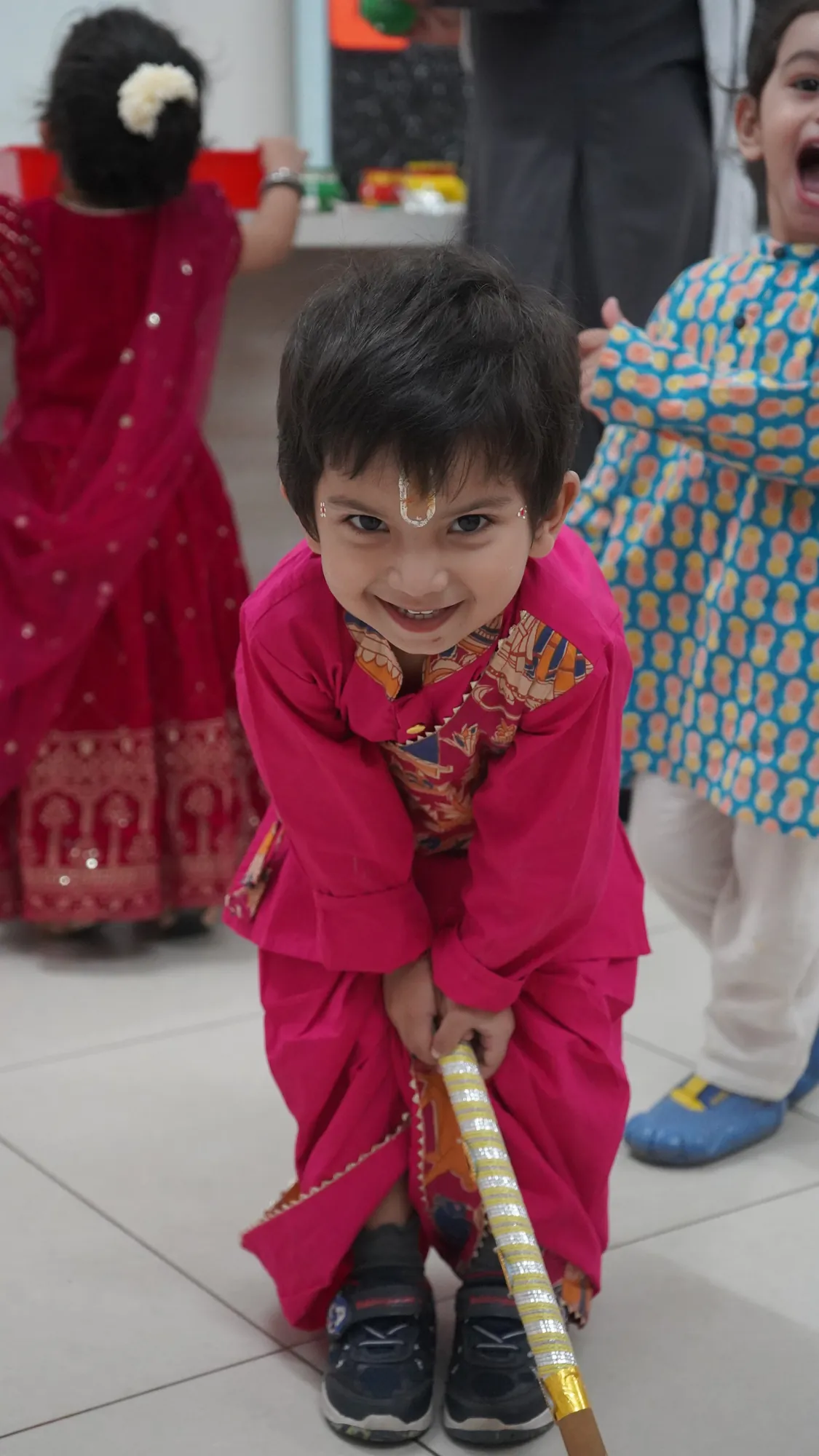 A young boy in a festive pink kurta, grinning