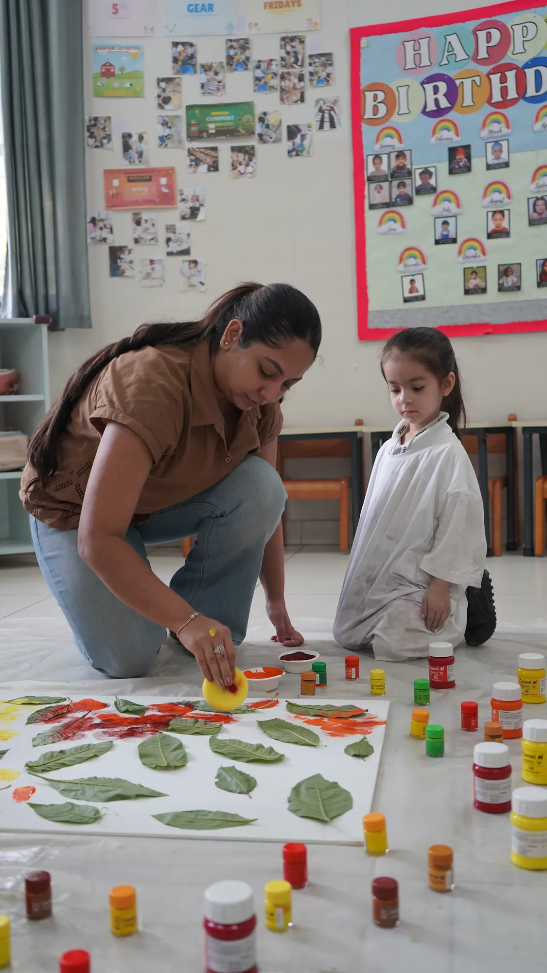 An educator and a child printing leaves with paint
