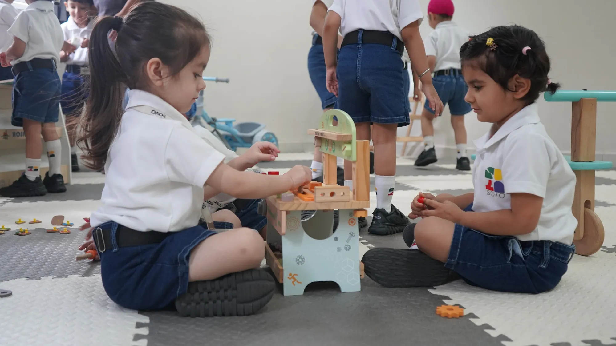 Young children each working at their own toy tool bench