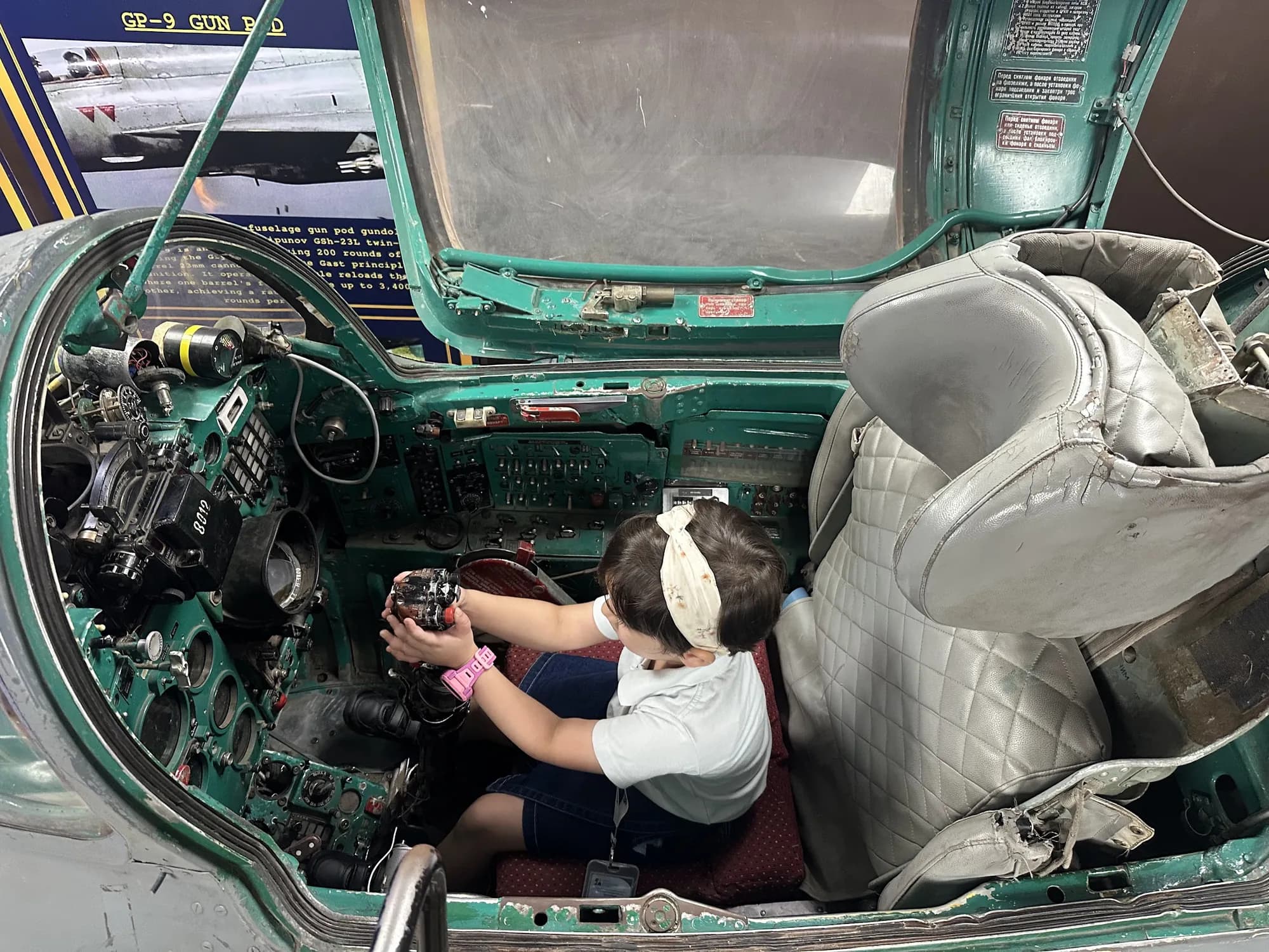 A young SOVO student at the controls of a fighter jet cockpit at the Air Force Museum
