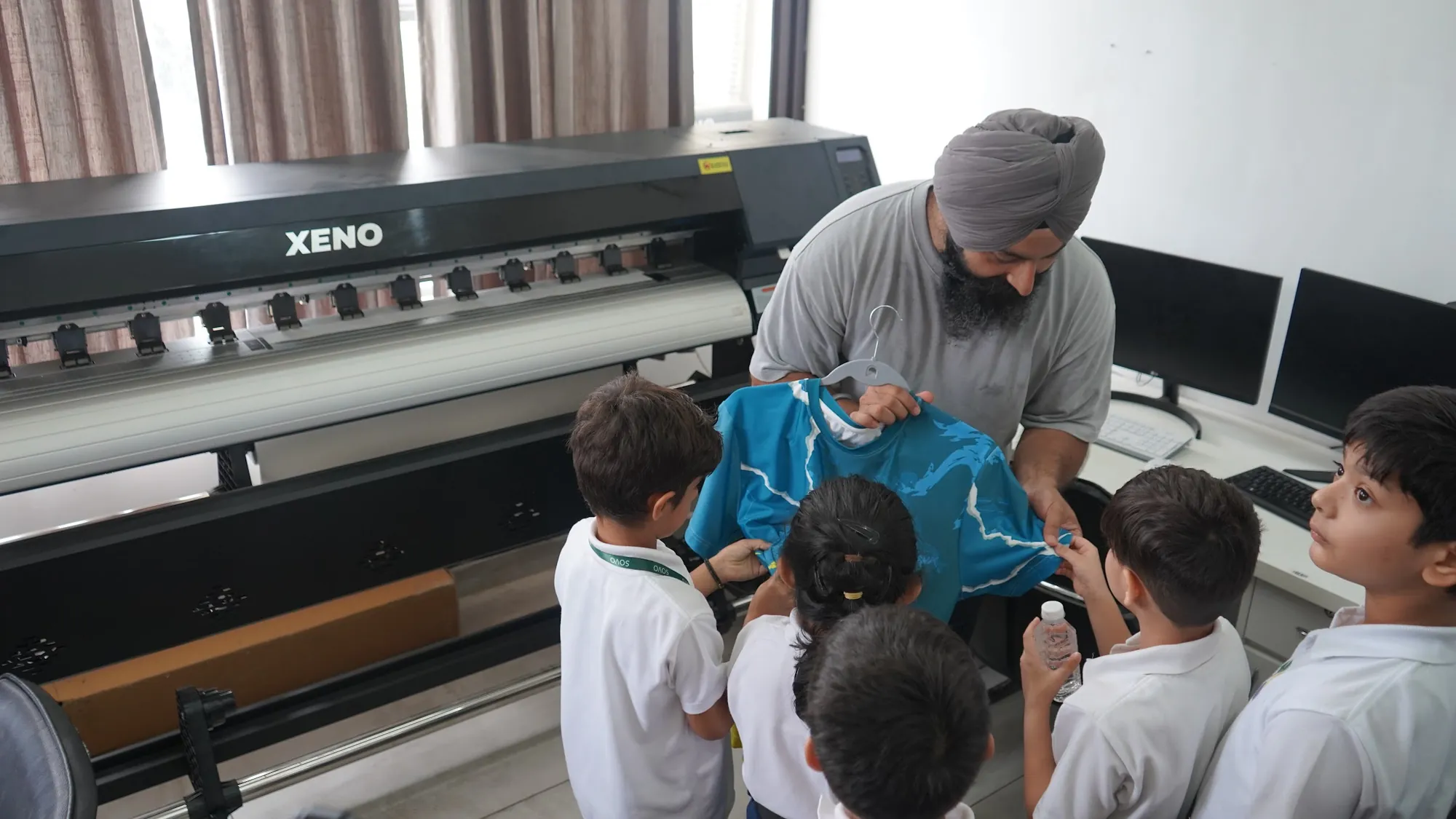 Students watching a fabric printer at the Fabtrax clothing factory