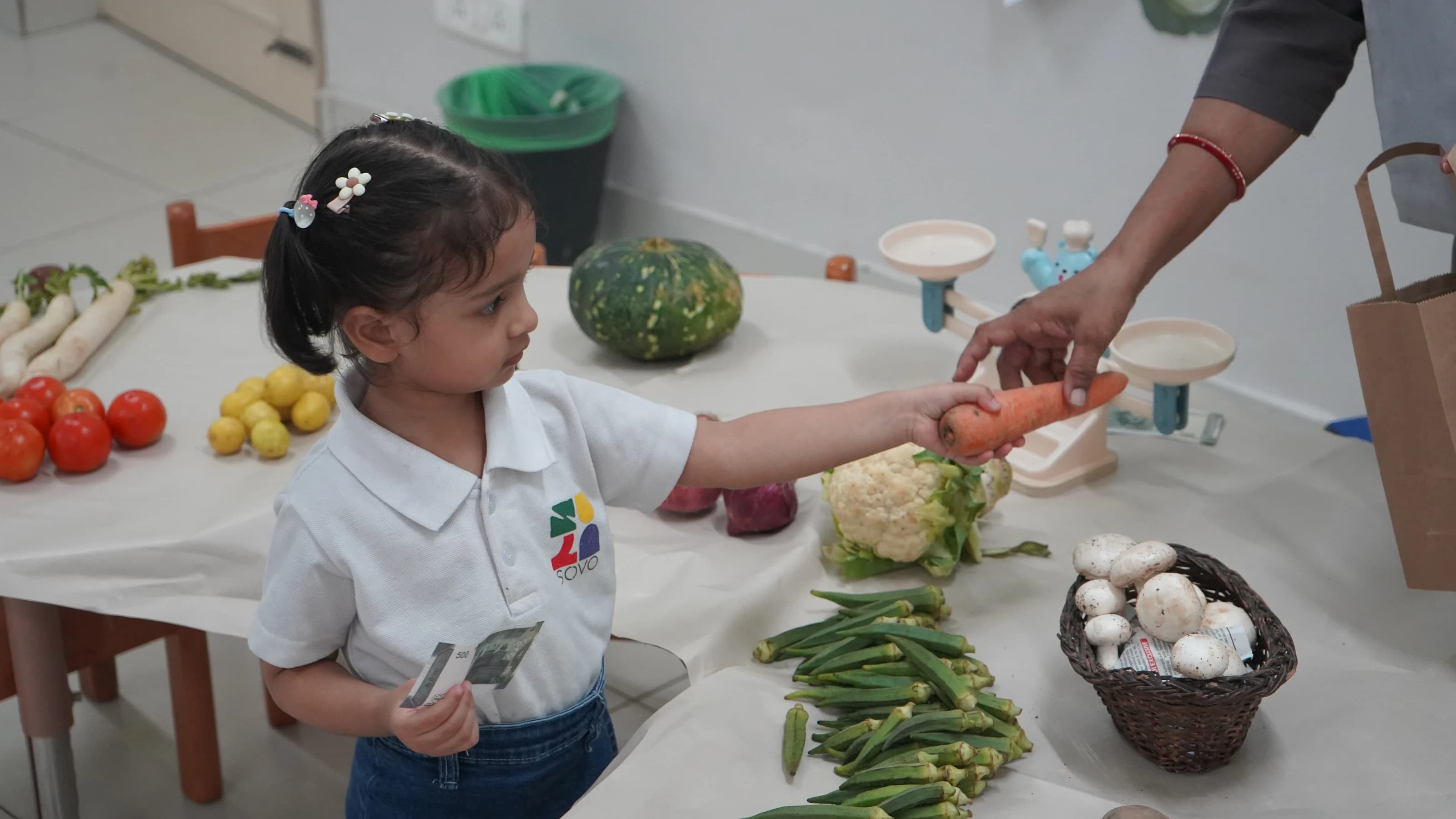 A young student buying fresh vegetables at a classroom market