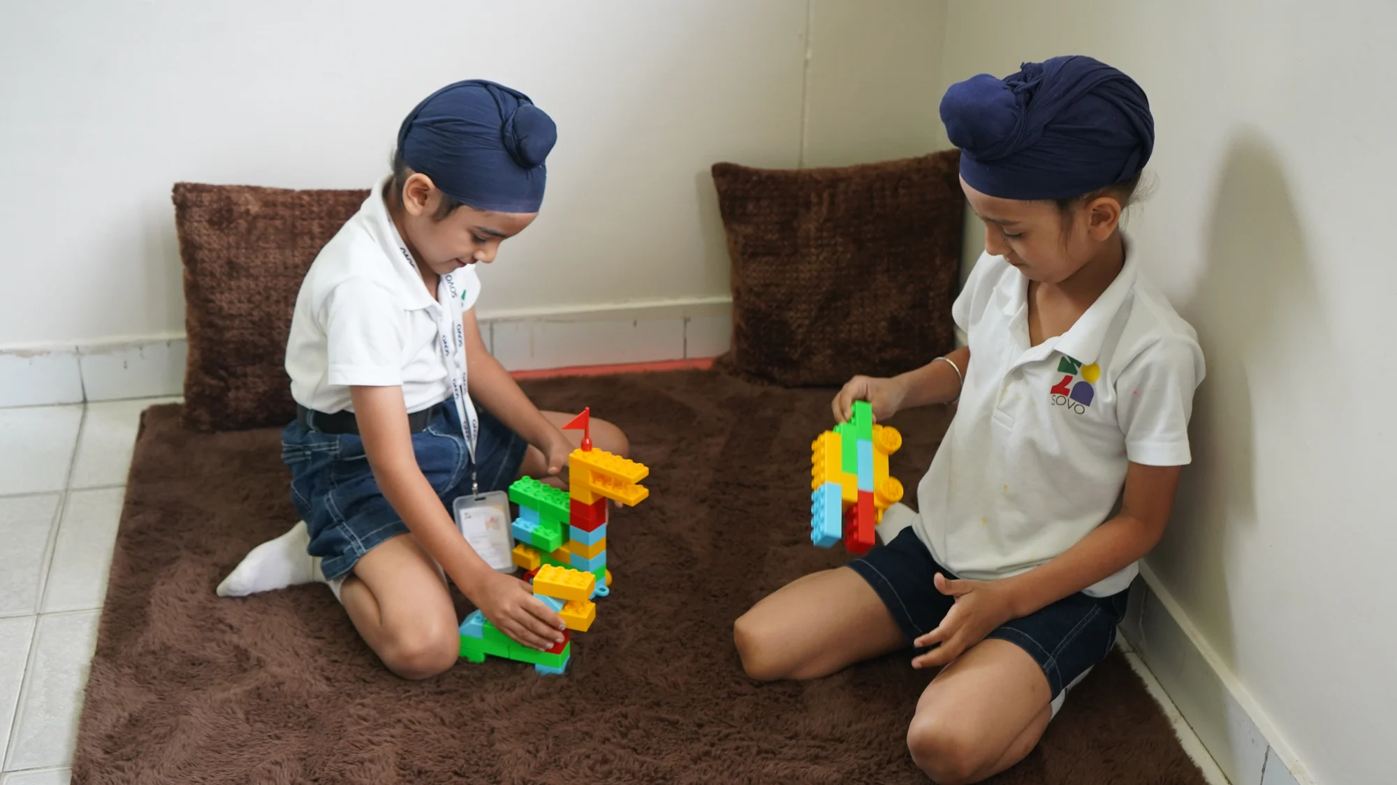Two SOVO students exploring colourful block constructions in their classroom
