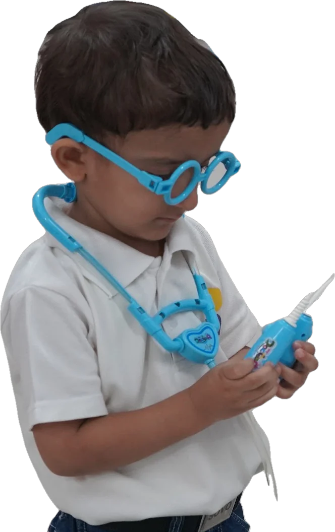 A young SOVO student in toy glasses and a stethoscope, closely examining a toy instrument