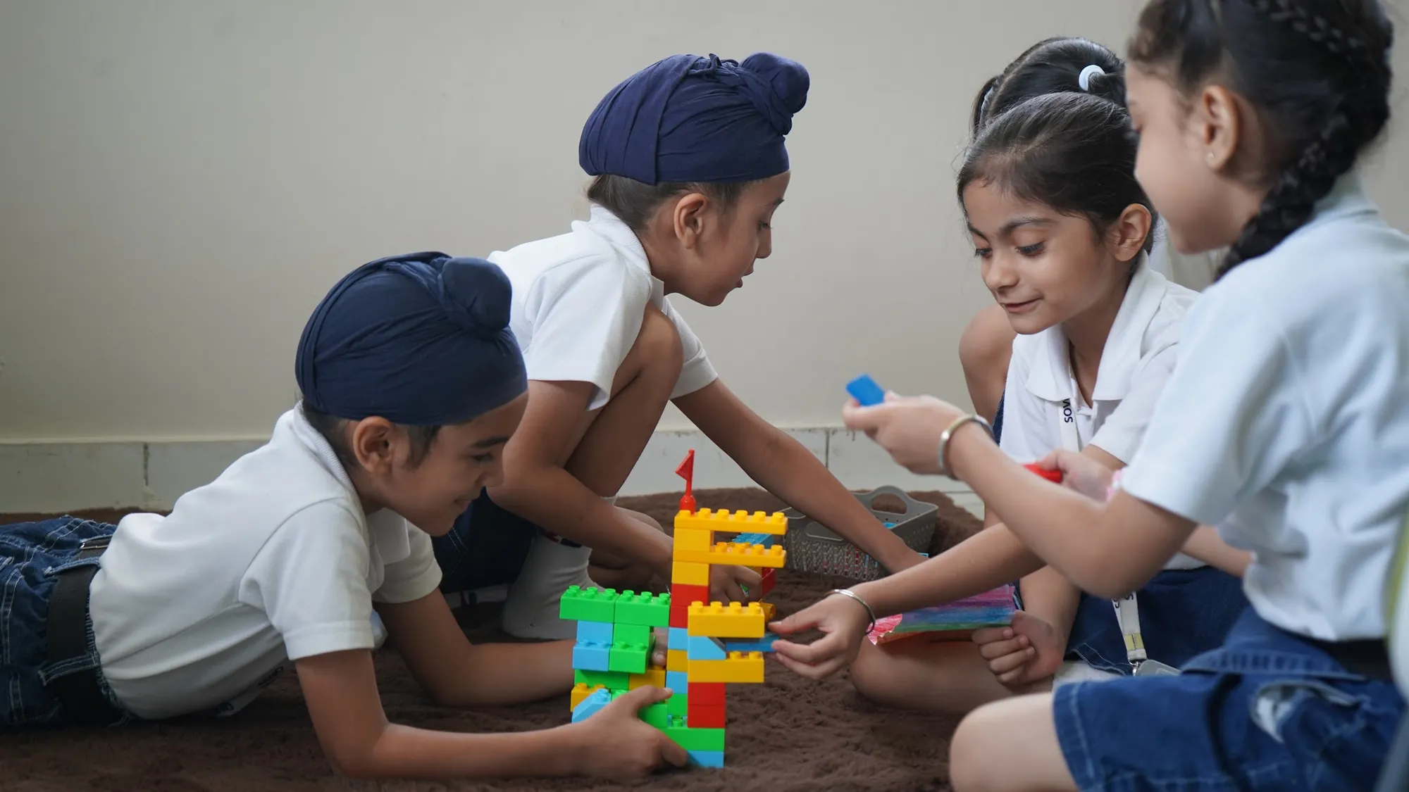 Students building a structure together on the classroom floor