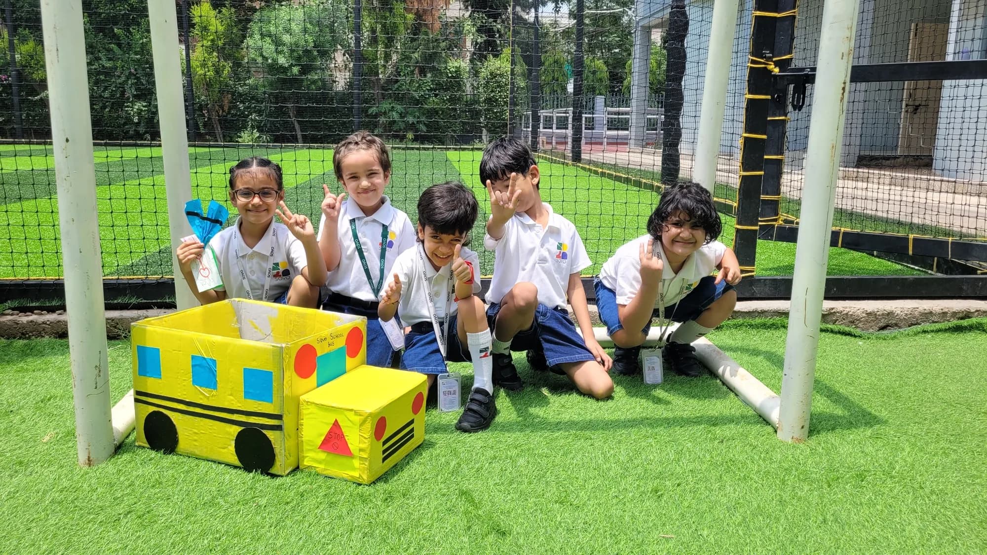 Students outdoors with the cardboard school bus they built together