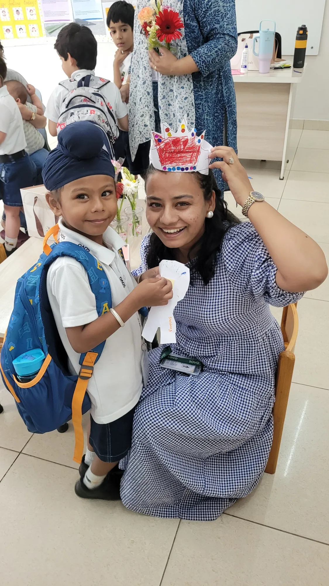 A SOVO educator smiling beside a student in his paper birthday crown